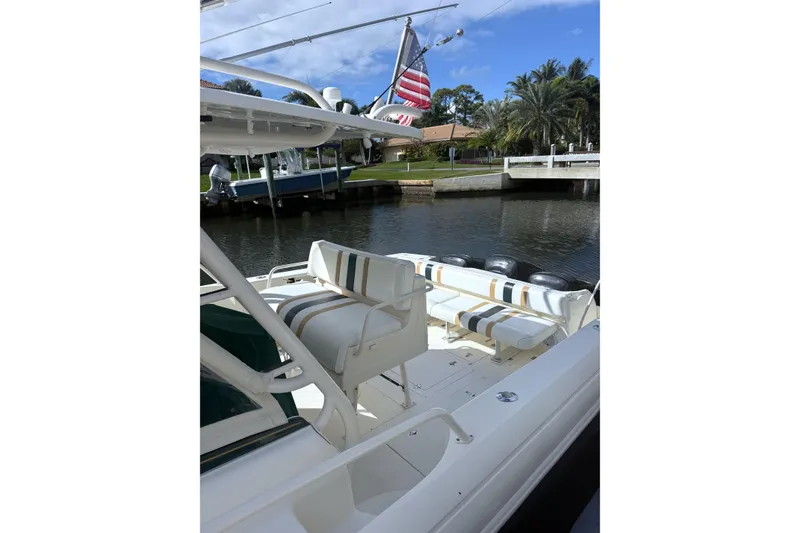 Slide: The Image of 2004 Intrepid 377 Walkaround boat with striped seating, docked by a canal. - 5