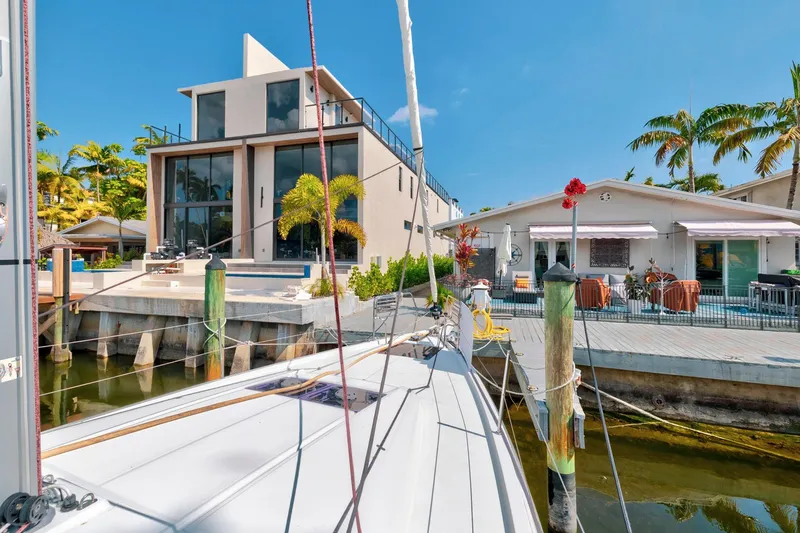 Slide: The Image of Modern waterfront home with Jeanneau Sun Odyssey 440 sailboat docked, surrounded by palm trees. - 21