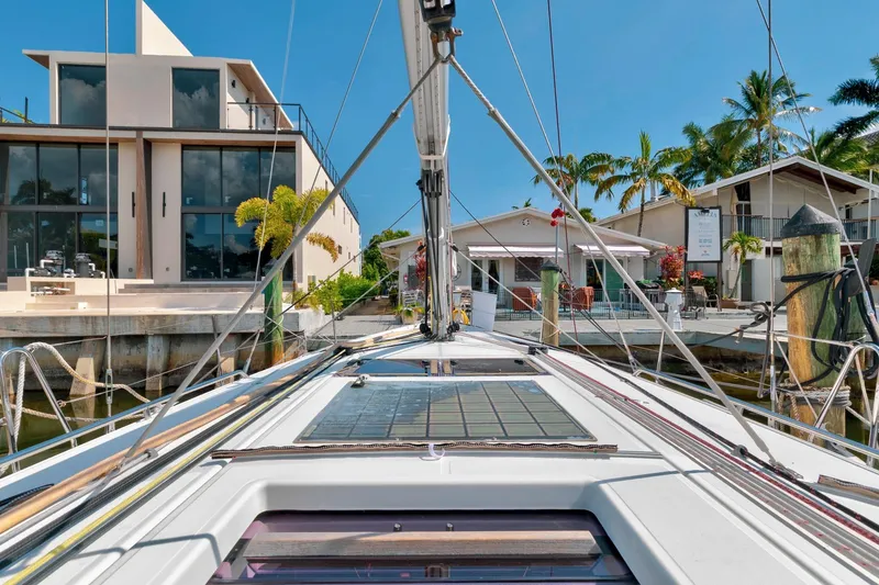 Slide: The Image of 2021 Jeanneau Sun Odyssey 440 docked near modern waterfront homes, clear blue sky. - 24