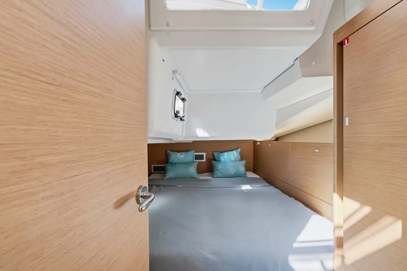 Slide: The Image of 2021 Jeanneau Sun Odyssey 440 cabin interior with modern wood finish and cozy bedding. - 45