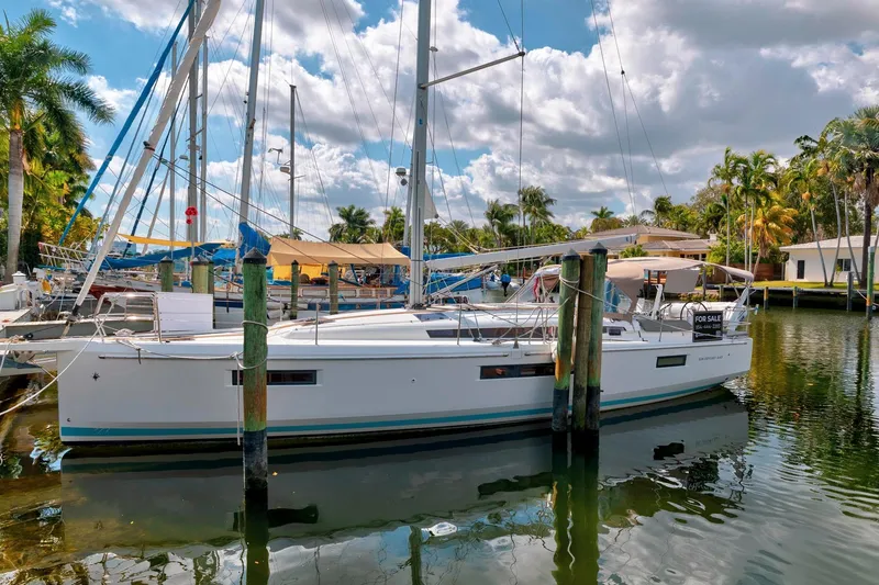 Slide: The Image of 2021 Jeanneau Sun Odyssey 440 sailboat docked, surrounded by palm trees and clear skies. - 6