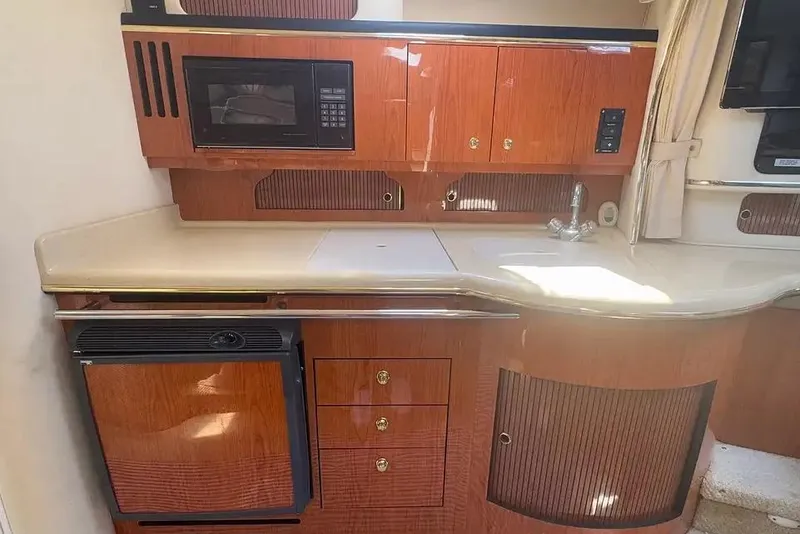 Slide: The Image of 2001 Sea Ray Sundancer 310 interior kitchen with wood cabinetry, microwave, and compact fridge. - 7