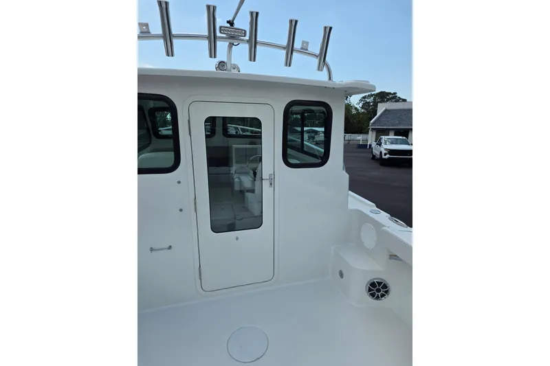 Slide: The Image of 2026 Parker 247 Explorer boat with enclosed cabin and rod holders, docked outdoors. - 14