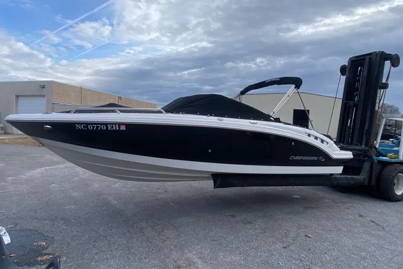 Slide: The Image of 2018 Chaparral 227 SSX boat on forklift, black hull, overcast sky background. - 2