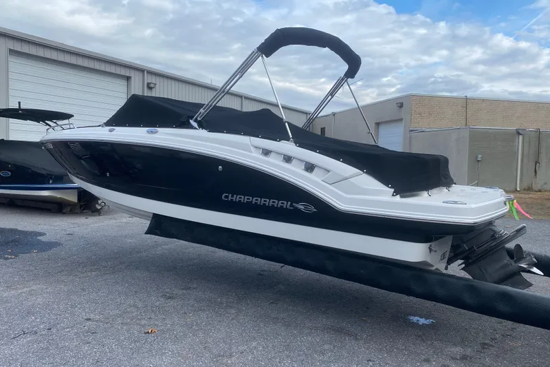 Slide: The Image of 2018 Chaparral 227 SSX boat with black cover, parked outdoors near a warehouse. - 3