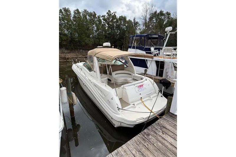 The Image of 2003 Sea Ray 340 Sundancer docked, featuring a beige canopy and spacious deck. - 0