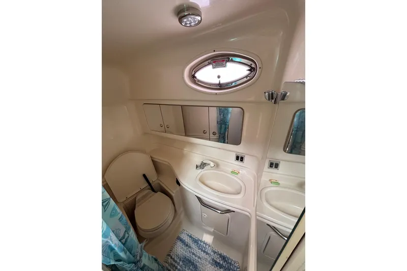 Slide: The Image of Bathroom interior of 2003 Sea Ray 340 Sundancer yacht, featuring sink, toilet, and porthole window. - 15