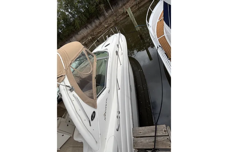 Slide: The Image of 2003 Sea Ray 340 Sundancer docked, featuring beige canopy and sleek white design. - 2