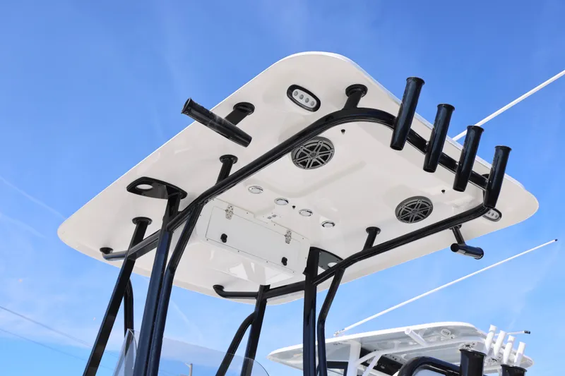 Slide: The Image of T-top of 2026 Sea Hunt Ultra 219 boat with rod holders and speakers against blue sky. - 5