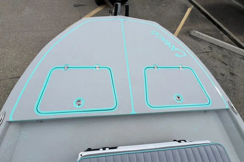 Slide: The Image of 2026 Cayuco Boats Lynx 18 deck with storage hatches and turquoise accents. - 13