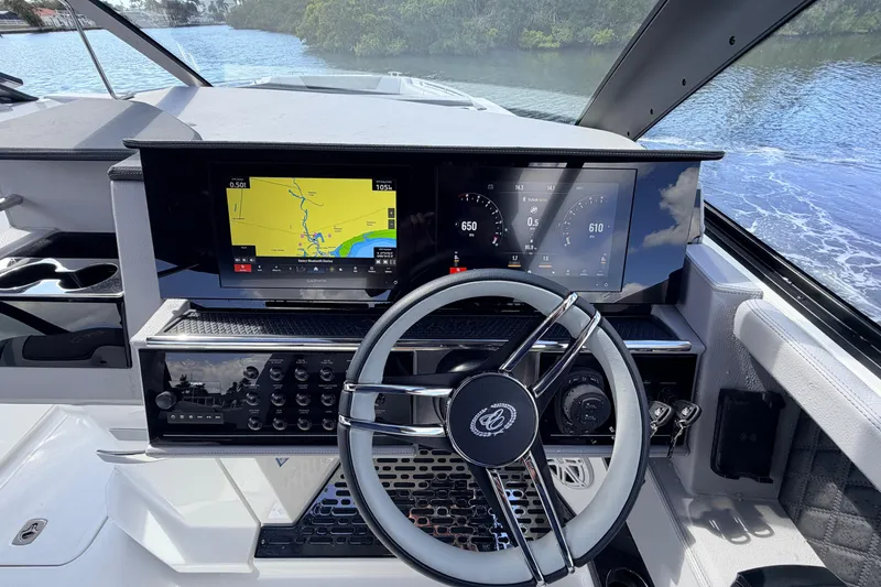 Slide: The Image of 2026 Cobalt R35 Outboard boat dashboard with dual screens and steering wheel on a scenic waterway. - 14