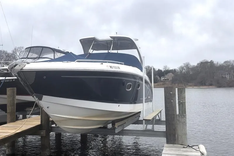 The Image of 2013 Chaparral 327 SSX boat docked on a lift by the water. - 0