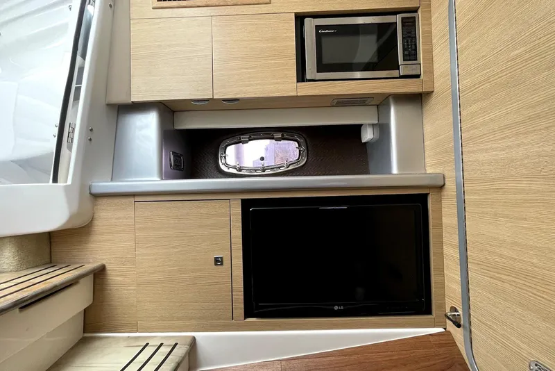 Slide: The Image of 2013 Chaparral 327 SSX interior with microwave, TV, and wooden cabinetry. - 8