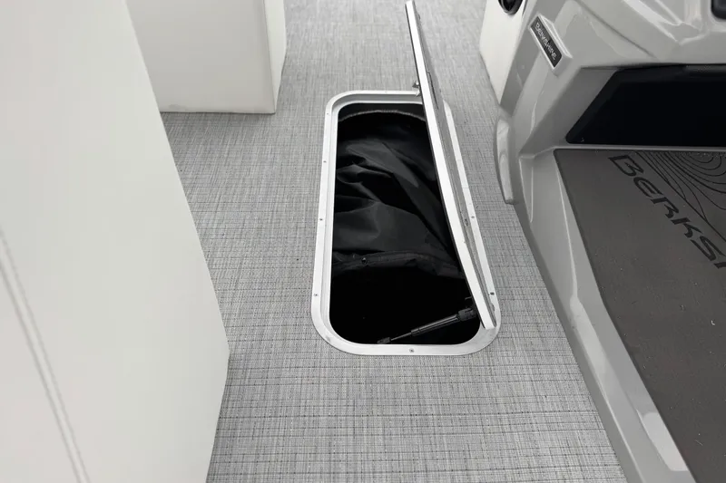 Slide: The Image of 2026 Berkshire 21CL STS boat interior with open storage compartment on gray flooring. - 24
