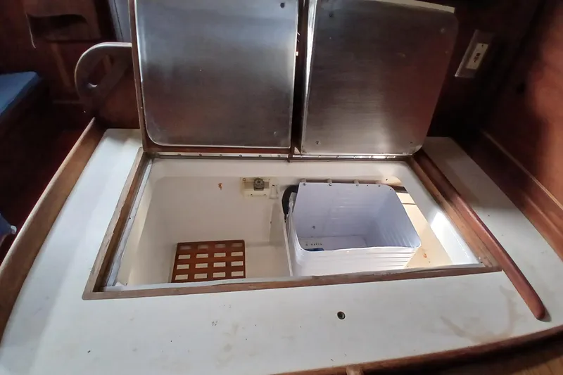 Slide: The Image of Open storage compartment on a 1977 Tartan 37 sailboat, featuring a metal lid and wooden trim. - 11