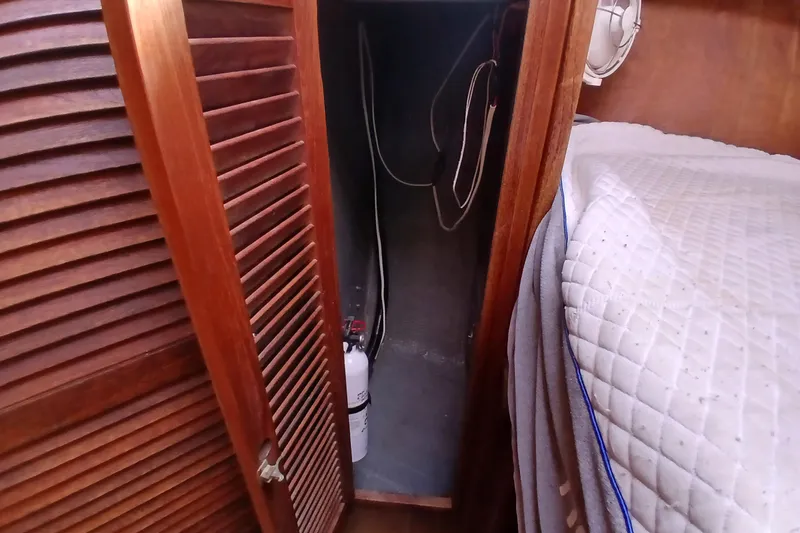 Slide: The Image of Wooden closet interior on a 1977 Tartan 37 sailboat, featuring a fire extinguisher. - 16