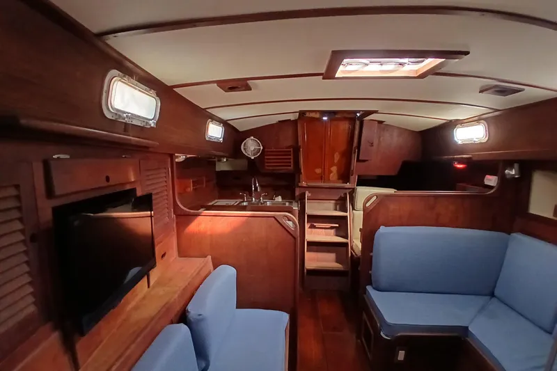 Slide: The Image of Interior of a 1977 Tartan 37 sailboat with wooden finish and blue seating. - 3