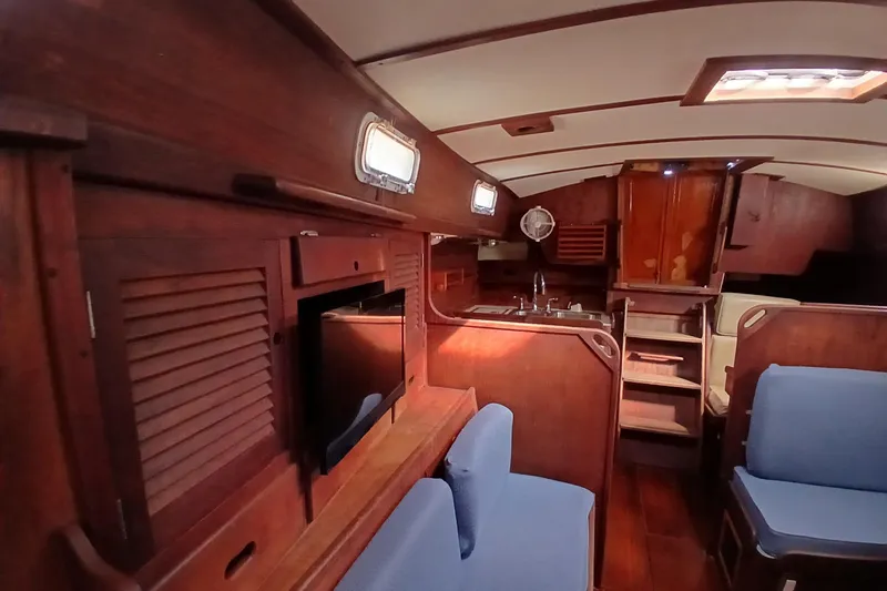 Slide: The Image of Interior of a 1977 Tartan 37 sailboat with wooden cabinetry and blue seating. - 4