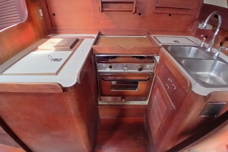 Slide: The Image of 1977 Tartan 37 yacht kitchen with stove, sink, and wooden cabinetry. - 9