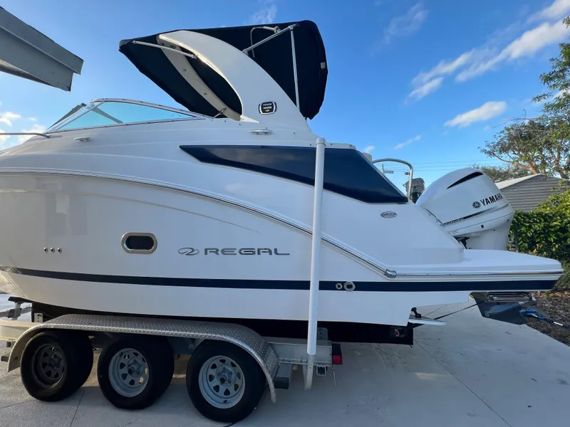 Slide: The Image of 2020 Regal 26 XO boat on trailer with Yamaha engine, parked outdoors. - 2