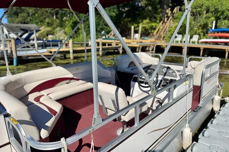Slide: The Image of 2008 Avalon Catalina 18' pontoon boat with maroon interior, docked by a wooden pier. - 1
