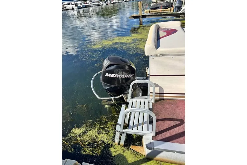 Slide: The Image of 2008 Avalon Catalina 18' boat with Mercury outboard motor docked on a lake. - 2