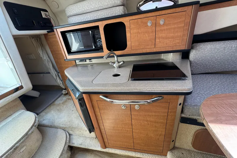 Slide: The Image of Interior of 2006 Sea Ray Sundancer 260 boat with kitchenette and seating area. - 26