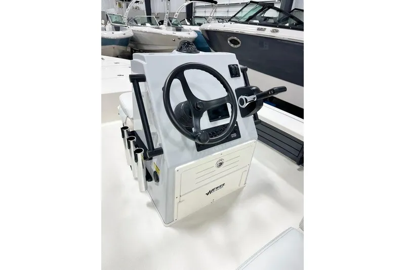 Slide: The Image of 2026 Hewes Redfisher 18 boat console with steering wheel and controls in showroom. - 7