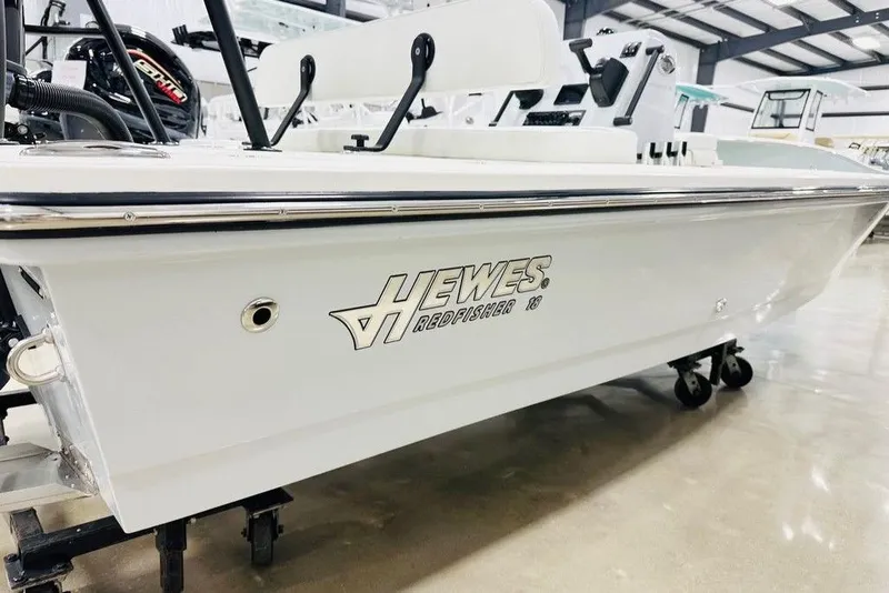 Slide: The Image of 2026 Hewes Redfisher 18 boat in showroom, side view with logo visible. - 8