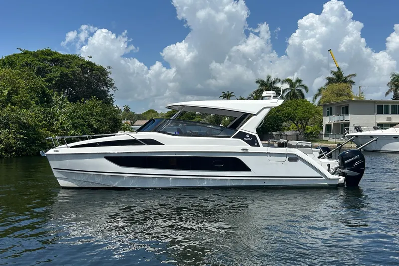 Slide: The Image of Aquila 36 Sport 2020 boat cruising on a sunny day with lush greenery background. - 0