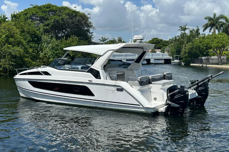 Slide: The Image of 2020 Aquila 36 Sport boat on a calm waterway, surrounded by lush greenery. - 1