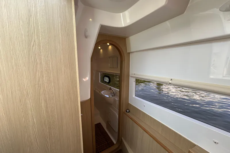 Slide: The Image of Interior of 2020 Aquila 36 Sport boat, featuring wood paneling and a compact bathroom. - 16