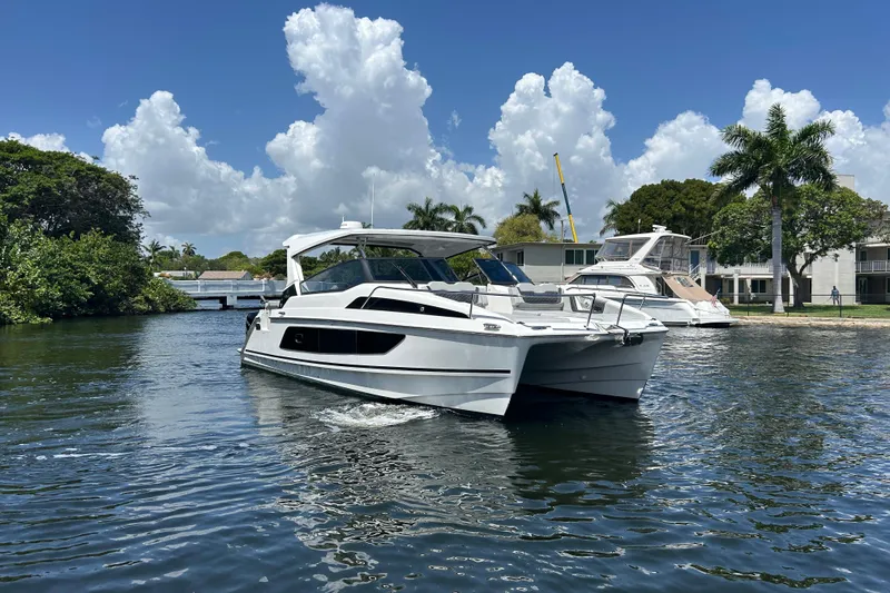 Slide: The Image of 2020 Aquila 36 Sport catamaran cruising on a sunny day with palm trees in the background. - 2