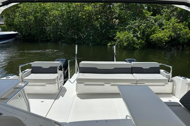 Slide: The Image of Aquila 36 Sport 2020 boat interior with seating and table, surrounded by lush greenery. - 5