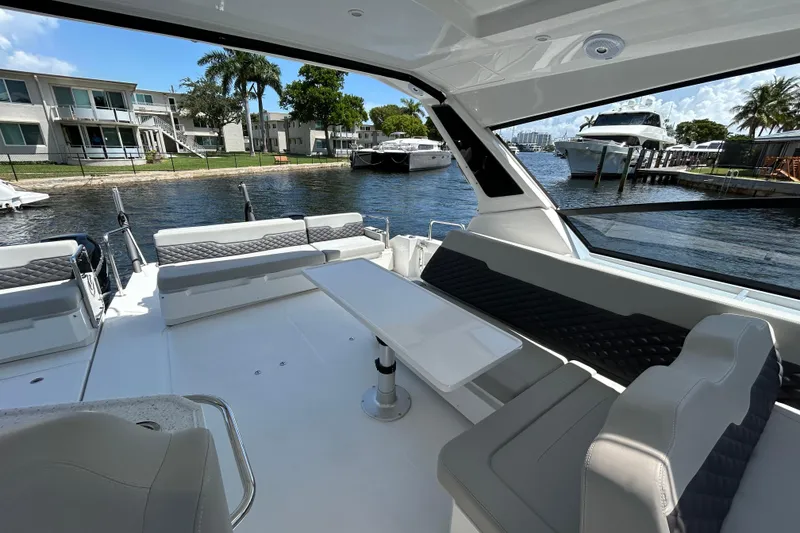 Slide: The Image of Aquila 36 Sport 2020 boat interior with seating and table, docked near waterfront homes. - 6
