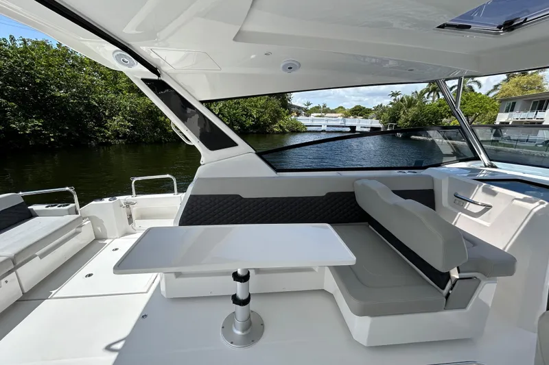 Slide: The Image of Aquila 36 Sport 2020 boat interior with seating and table, near a scenic waterway. - 7