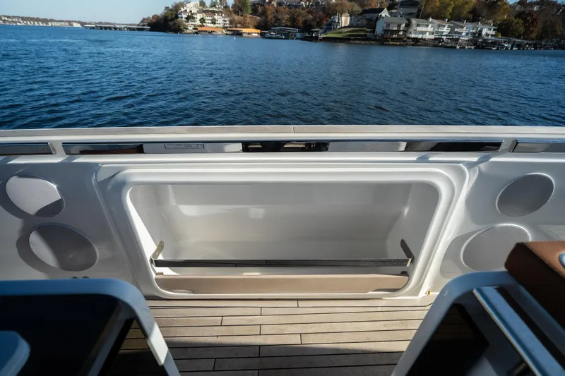 Slide: The Image of Invictus TT430 2025 yacht deck with open storage compartment, overlooking serene waters. - 26