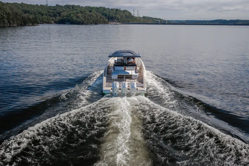 Slide: The Image of 2025 Invictus TT430 yacht cruising on a serene lake with lush green shoreline. - 14