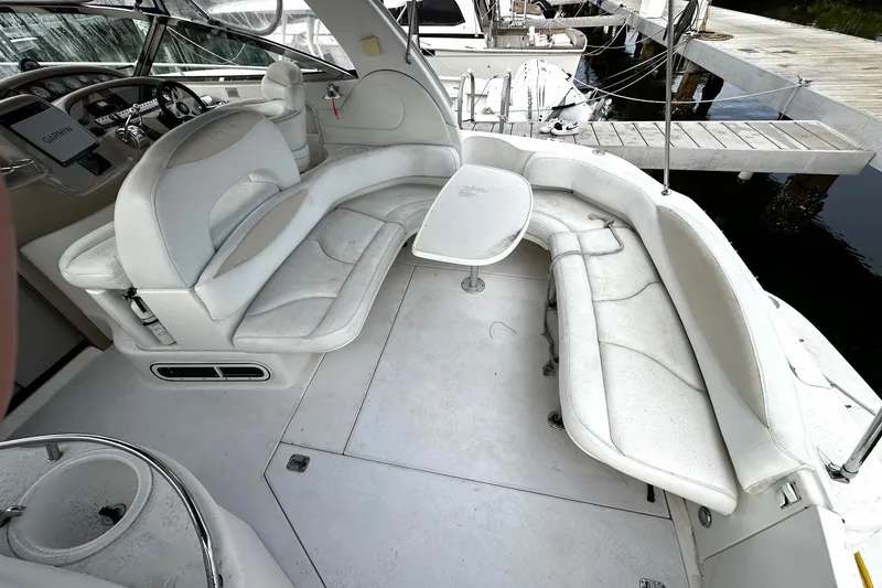 Slide: The Image of 2001 Sea Ray 380 Sundancer interior with white seating and table, docked at marina. - 12