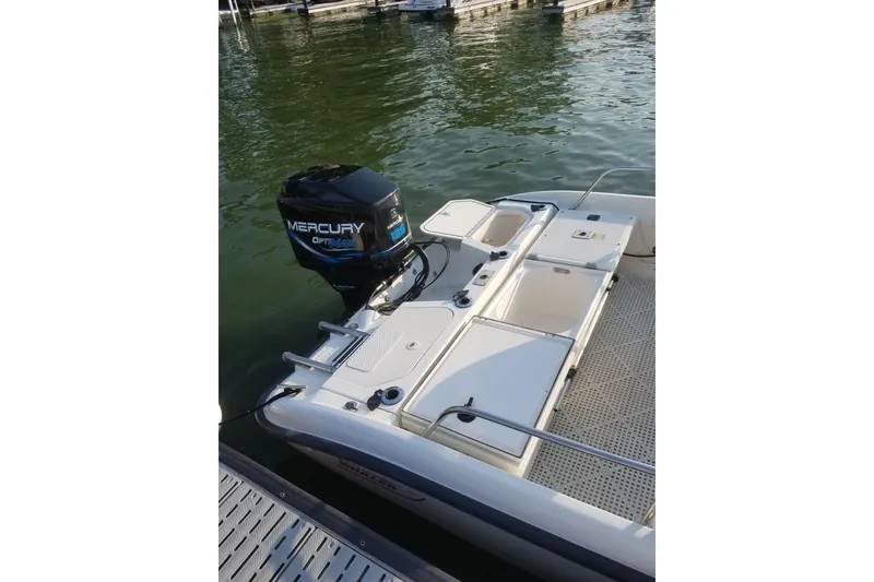 Slide: The Image of 1999 Boston Whaler 180 Dauntless with Mercury Optimax engine, docked on calm water. - 16