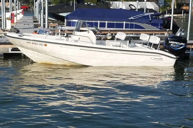 Slide: The Image of 1999 Boston Whaler 180 Dauntless boat docked, featuring a Mercury outboard motor. - 3