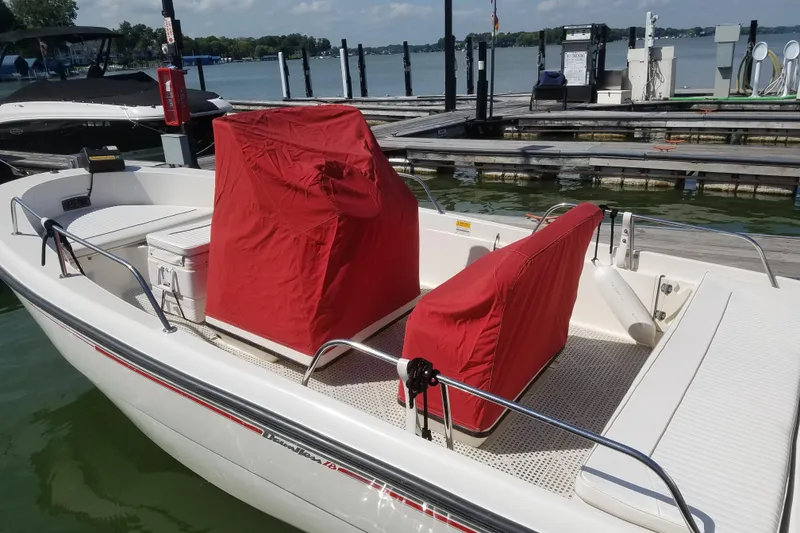 Slide: The Image of 1999 Boston Whaler 180 Dauntless boat docked, featuring red seat covers. - 4