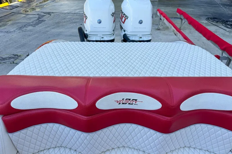 Slide: The Image of 2022 Velocity 290sc boat with red and white quilted seating and dual outboard motors. - 100
