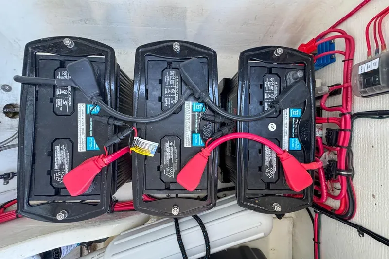 Slide: The Image of Three marine batteries in a 2022 Velocity 290sc boat, connected with red and black cables. - 107