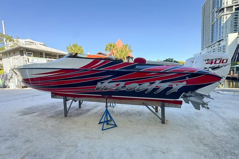 Slide: The Image of 2022 Velocity 290sc speedboat with vibrant red and blue design, docked outdoors. - 14
