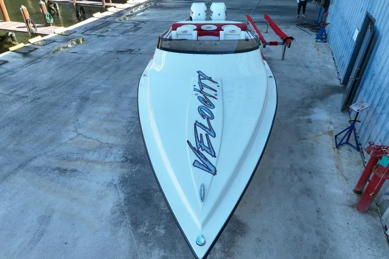 Slide: The Image of 2022 Velocity 290sc speedboat on concrete dock, showcasing sleek design and branding. - 18