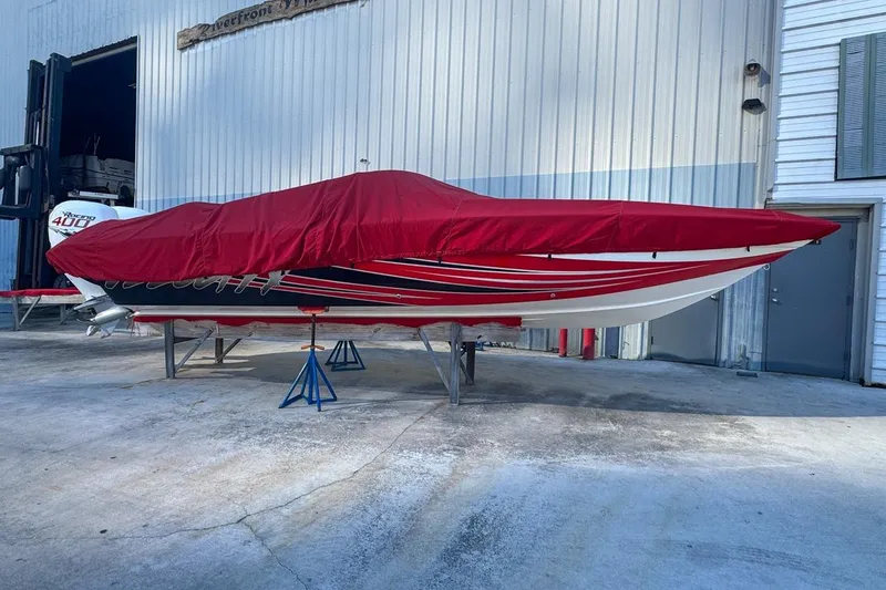 Slide: The Image of 2022 Velocity 290sc boat covered in red tarp, stored on stands outside a building. - 19