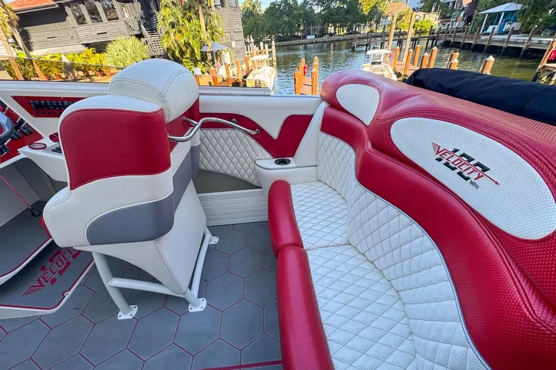 Slide: The Image of 2022 Velocity 290sc boat interior with red and white seating, dockside view. - 28