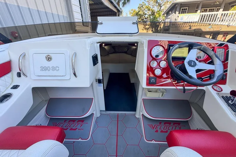 Slide: The Image of 2022 Velocity 290SC boat interior with red accents and steering wheel. - 36