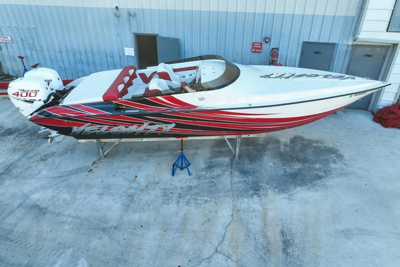 Slide: The Image of 2022 Velocity 290sc speedboat with red and black design, parked on concrete. - 4